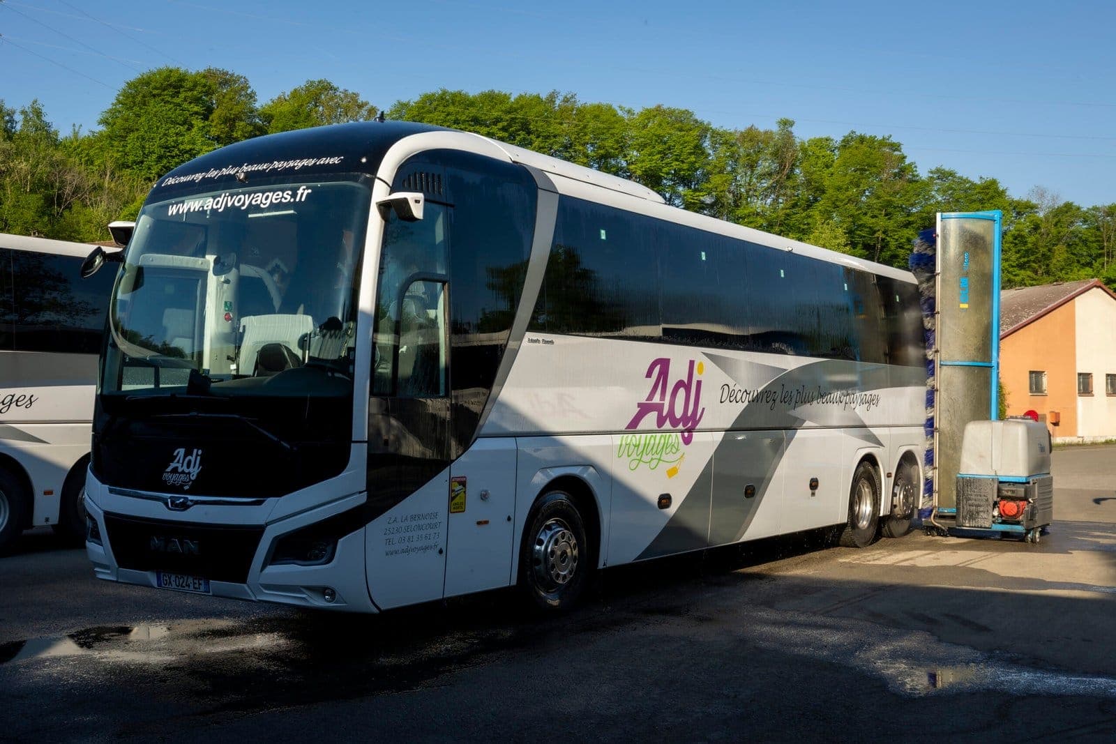 Autocars ADJ Voyages stationnés devant les portes de l'atelier d'entretien