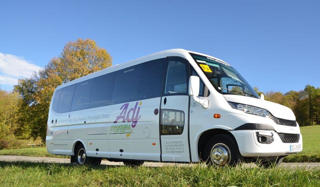 Minibus Ferqui 24 places d'ADJ Voyages vu de trois quarts avant dans un pré