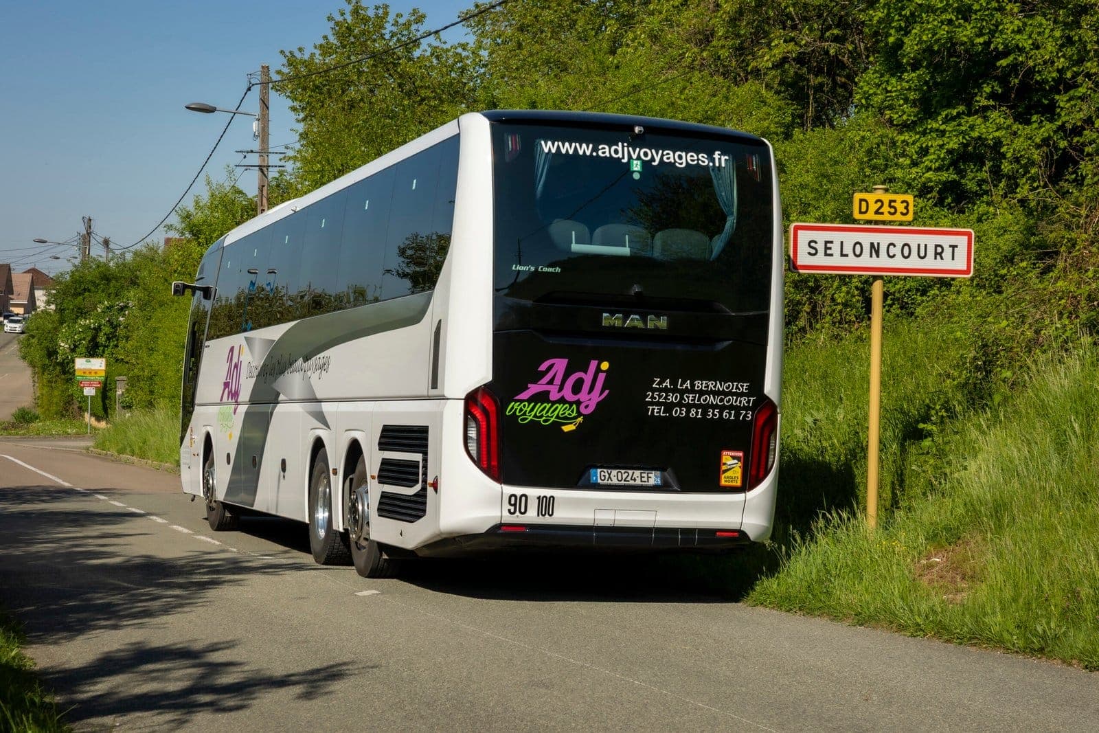 Arrière d’un autocar MAN ADJ Voyages devant le panneau d’entrée de Seloncourt