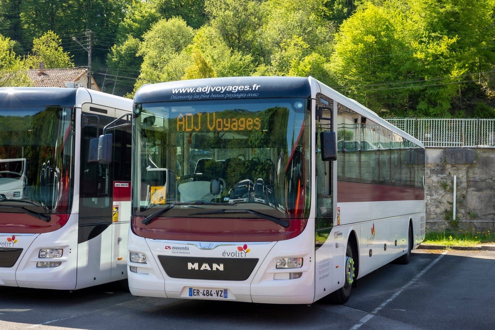 Autocar MAN rouge et blanc affichant ADJ Voyages sur sa girouette avant