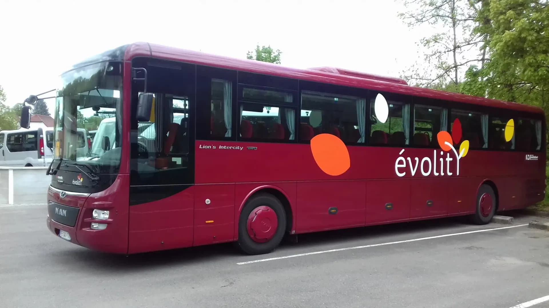Autocar MAN rouge de la livrée Évolit vu de profil