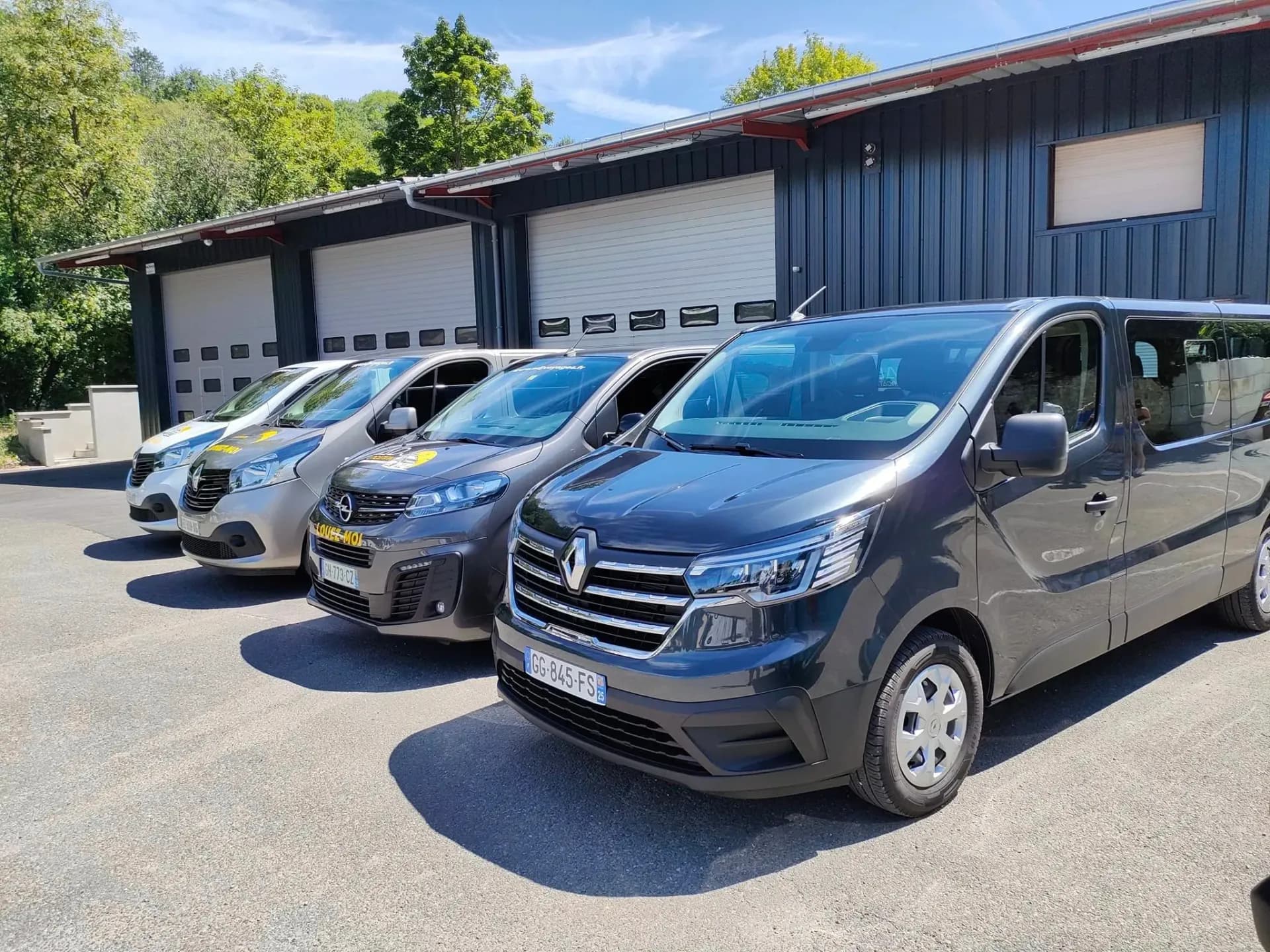 Flotte de minibus et navettes ADJ Voyages alignés devant le dépôt de Seloncourt