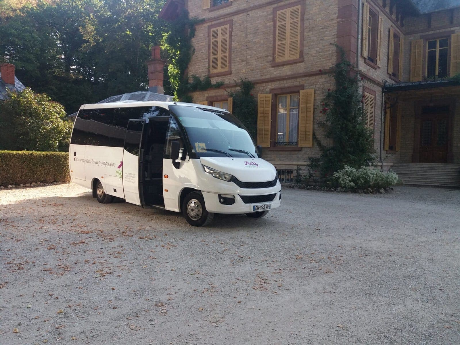 Minibus Iveco 28 places d’ADJ Voyages devant un manoir